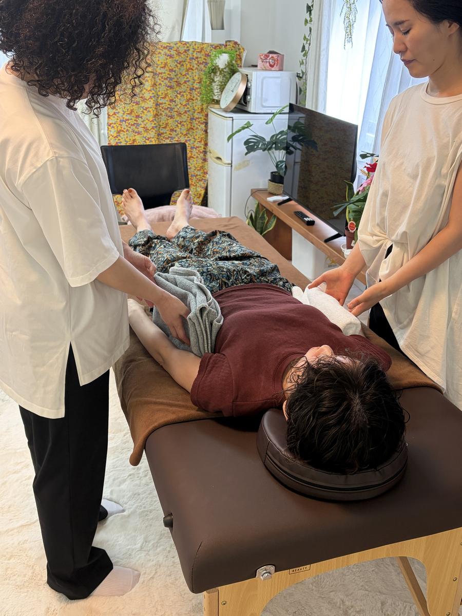 二人の受講生が仰向けのモデルに手技を練習している様子